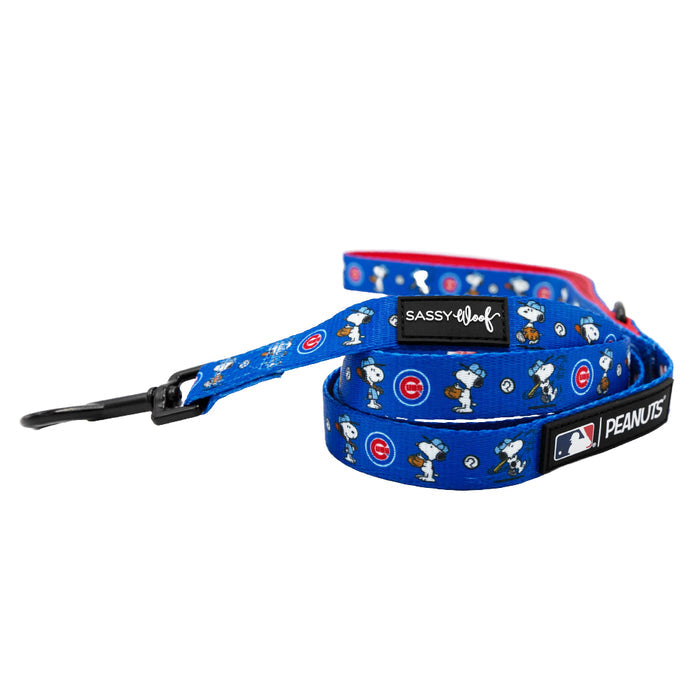 The Sassy Woof Harness Three Piece Bundle - MLB™ x Peanuts™ Chicago Cubs™ features a blue design with Snoopy baseball and Cubs logos, red accents, branded labels, a black metal clasp, and matching collar and harness for your dog.