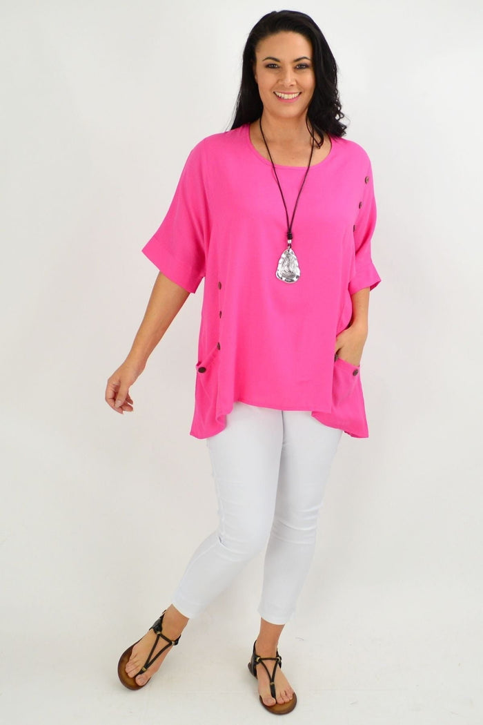 Hot pink Wishstone tunic top with coconut buttons and sloping sleeves, displayed on a woman against a neutral background.