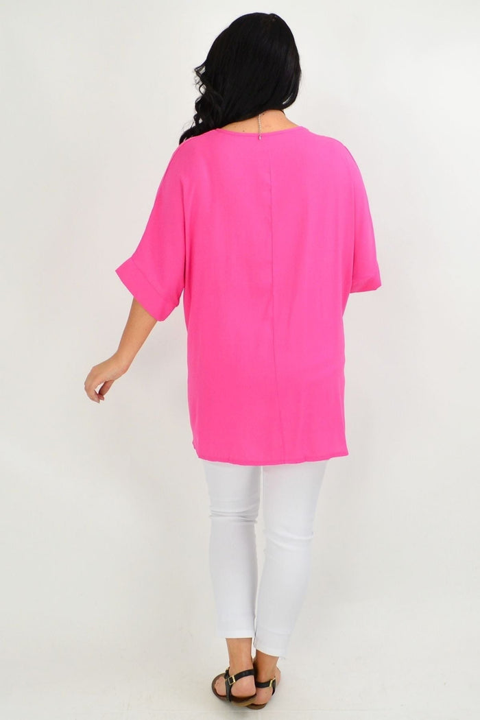 Hot pink Wishstone tunic top with coconut buttons and sloping sleeves, shown on a woman modeling the stylish women's tunic.