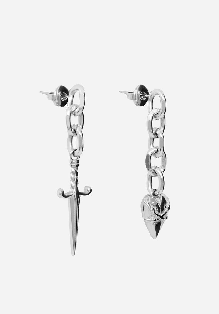 A pair of silver-toned chain dangle earrings, one featuring a pointed dagger charm and the other a skull charm, shown against a light gray background.