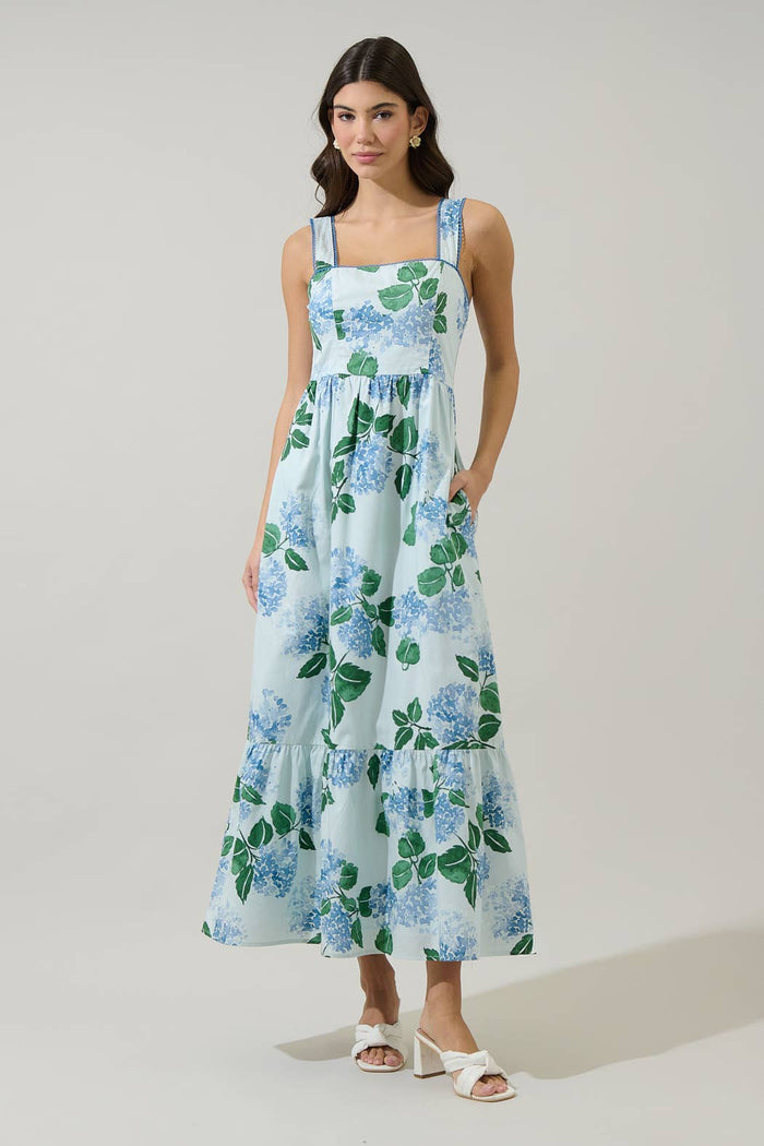 Woman wearing a long blue and green floral dress with hydrangeas with a white background