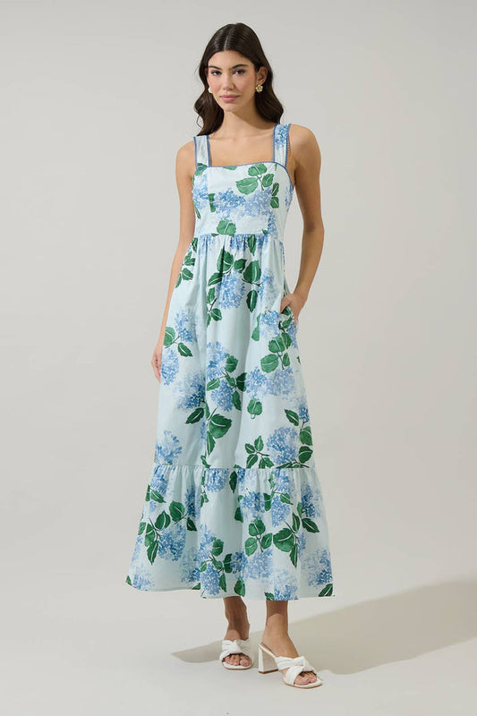 Woman wearing a long blue and green floral dress with hydrangeas with a white background