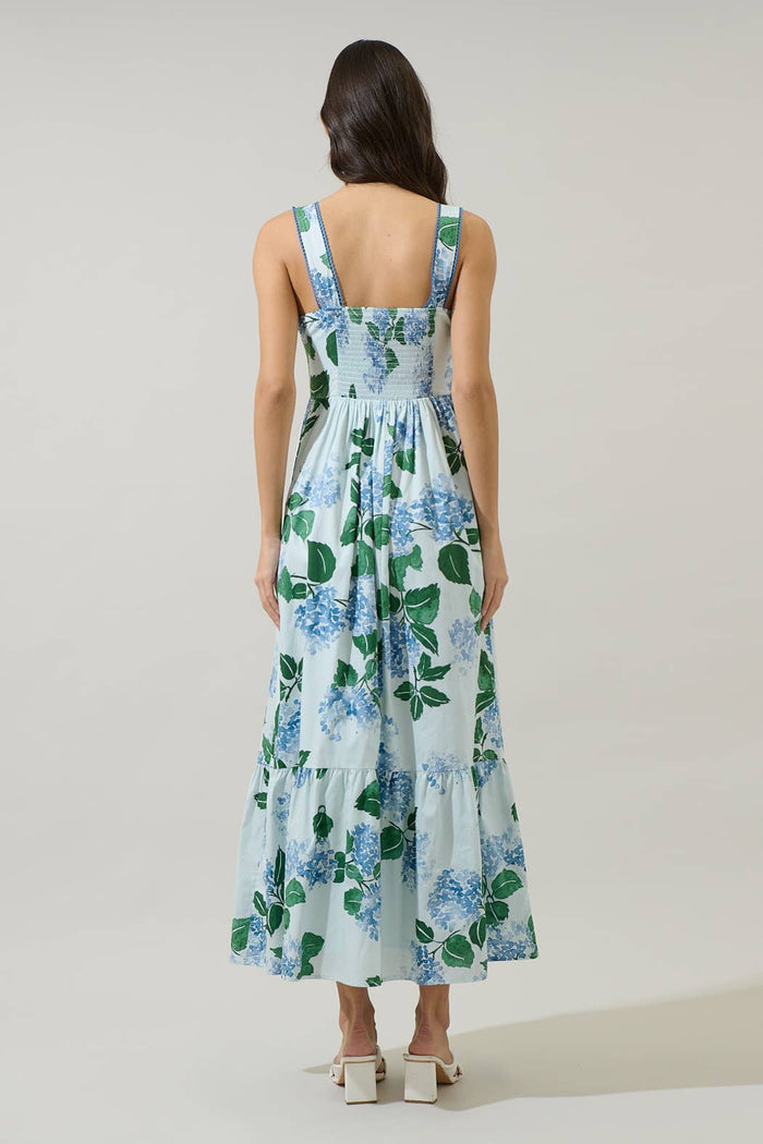 Woman wearing a long blue and green floral dress with hydrangeas with a white background