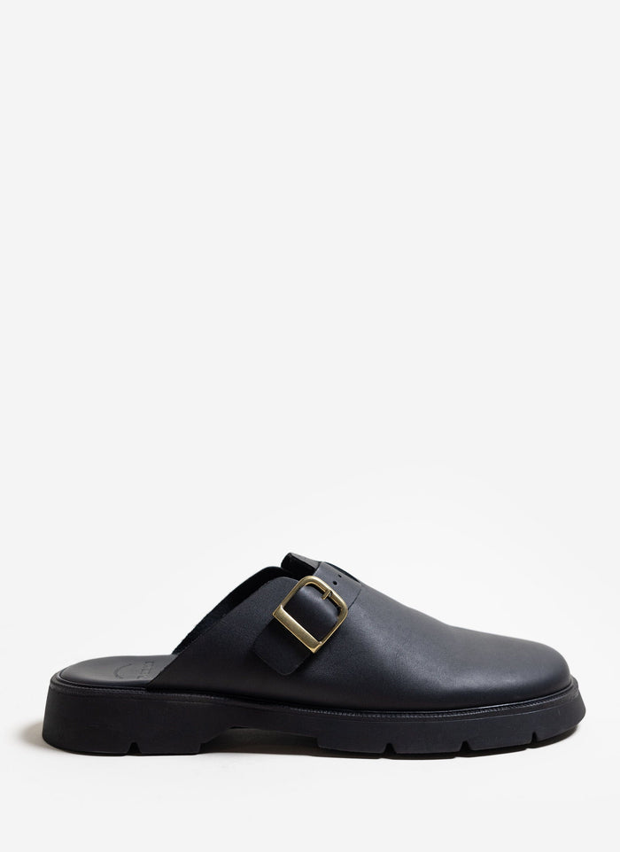 A side view of the black leather Kleman Pacha sandal with its gold buckle and thick sole, from Percival.