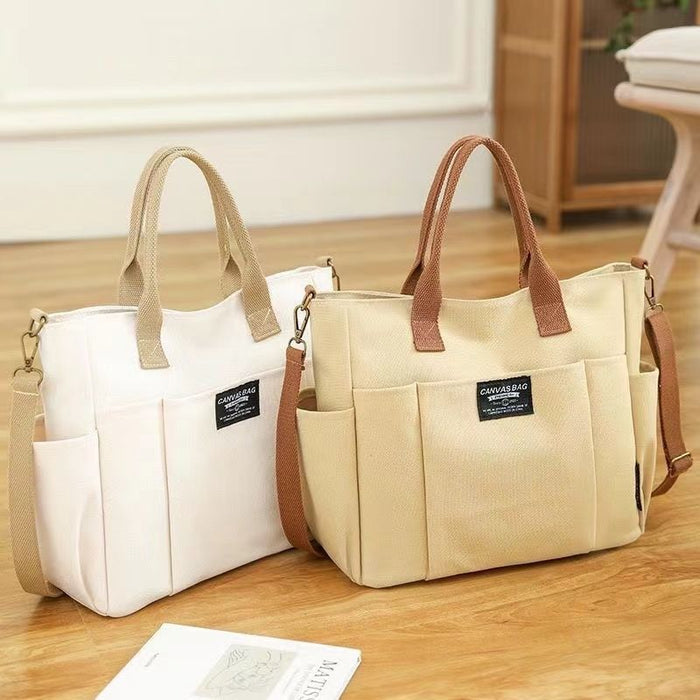 Big canvas shoulder bag showing its rectangular shape, top handles, adjustable strap and front pocket for organized carrying.