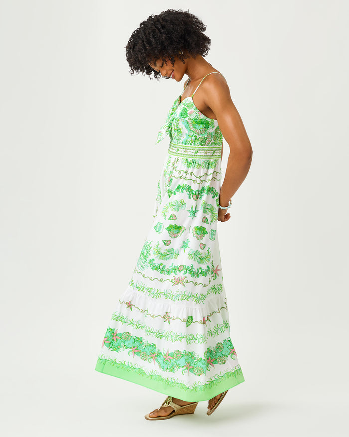 Woman wearing a green and white floral dress with front tie on a white background
