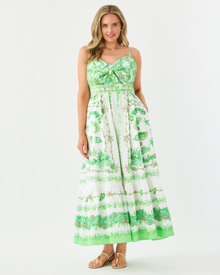 Woman wearing a green and white floral dress with front tie on a white background
