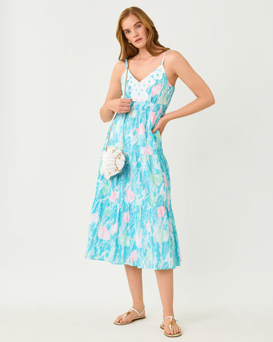 Woman wearing a blue floral dress with pink and white seashell details and white lace  on a white background
