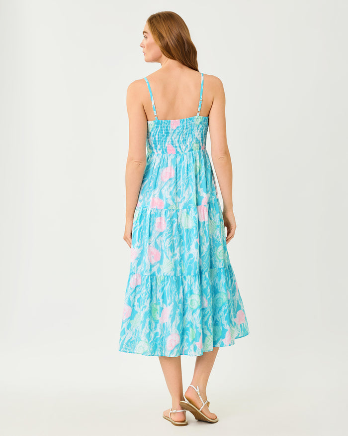 Woman wearing a blue floral dress with pink and white seashell details and white lace with adjustable straps on a white background