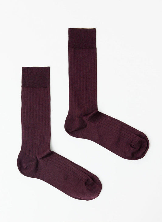 A pair of Percival Loafer Dress Socks in merlot, made from a ribbed cotton, laid flat against a white background.