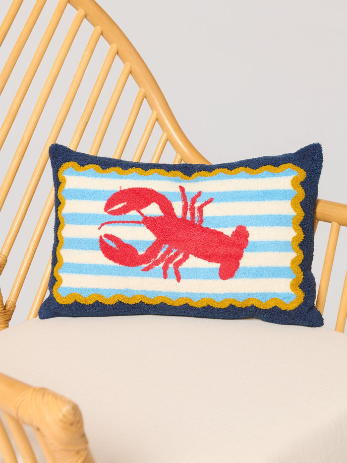Decorative navy pillow with a red lobster on a blue and white striped background with golden yellow trim