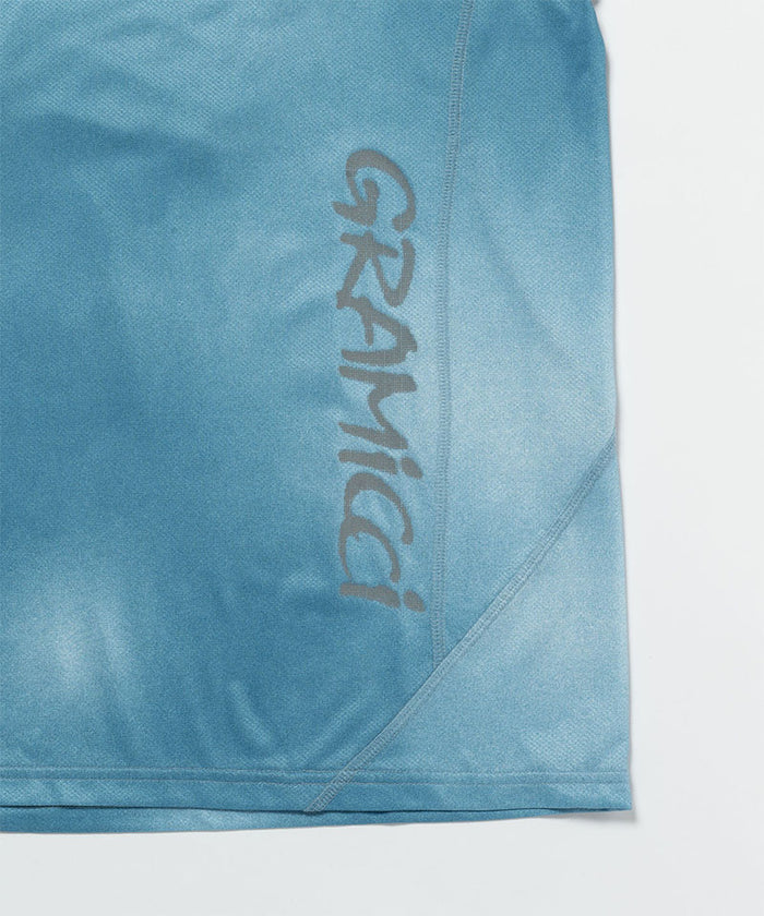 Gramicci blue tie-dye L/S 1st Layer shirt hem detail with a grey graphic against a light-tone background.