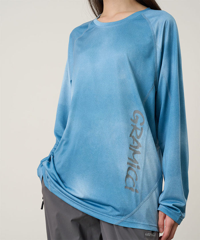 Model wearing a Gramicci blue tie-dye L/S 1st Layer shirt with grey graphic against a light-tone background.