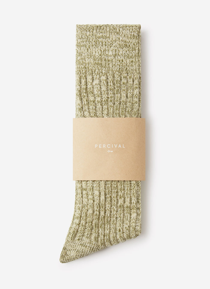 A pair of Percival Marl Socks in fern green, folded and held with a branded paper band against a white background.