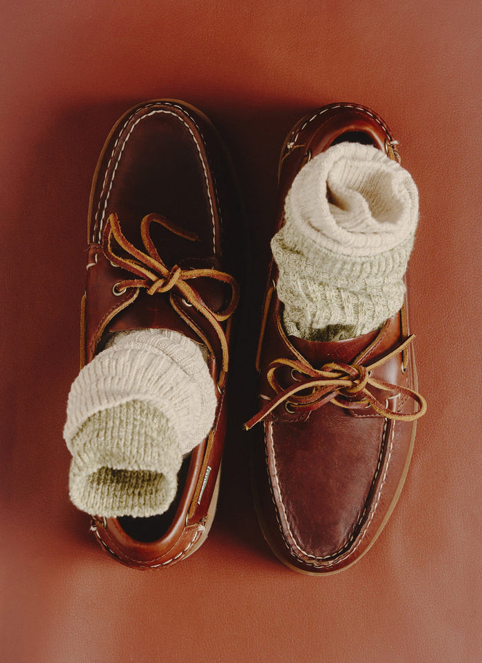 A top-down shot of the Percival Marl Socks in Fern Green, neatly folded inside a pair of classic brown leather boat shoes.