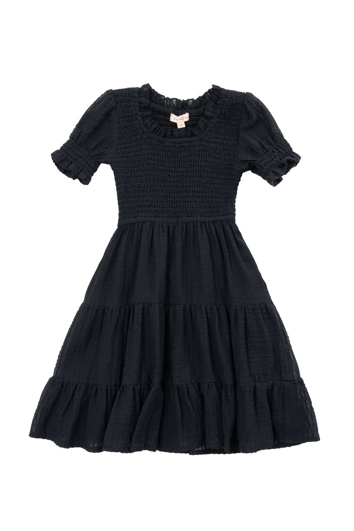 The Mini Ellery Dress in Black by Ivy City Co is a kids’ knee-length, short-sleeved dress with a smocked bodice, ruffled round neckline, tiered skirt, and ruffle trim—ideal for matching mom moments.
