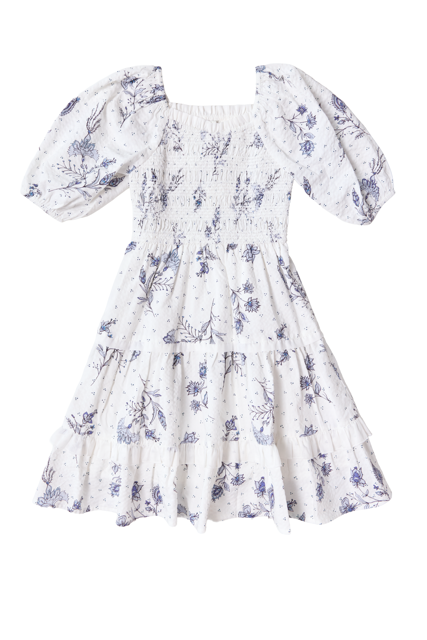 The Mini Roselyn Dress in Blue Enchanted Floral by Ivy City Co features white, short puffed sleeves, a smocked bodice, and a tiered flared skirt for a feminine spring look—perfect for warmer days.