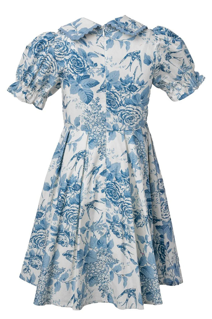 The Ivy City Co Mini Sophia Dress in Blue Floral features puffed sleeves, a fitted waist, pleated skirt, pointed collar, and a charming floral and bird print—ideal as a girls’ spring dress.