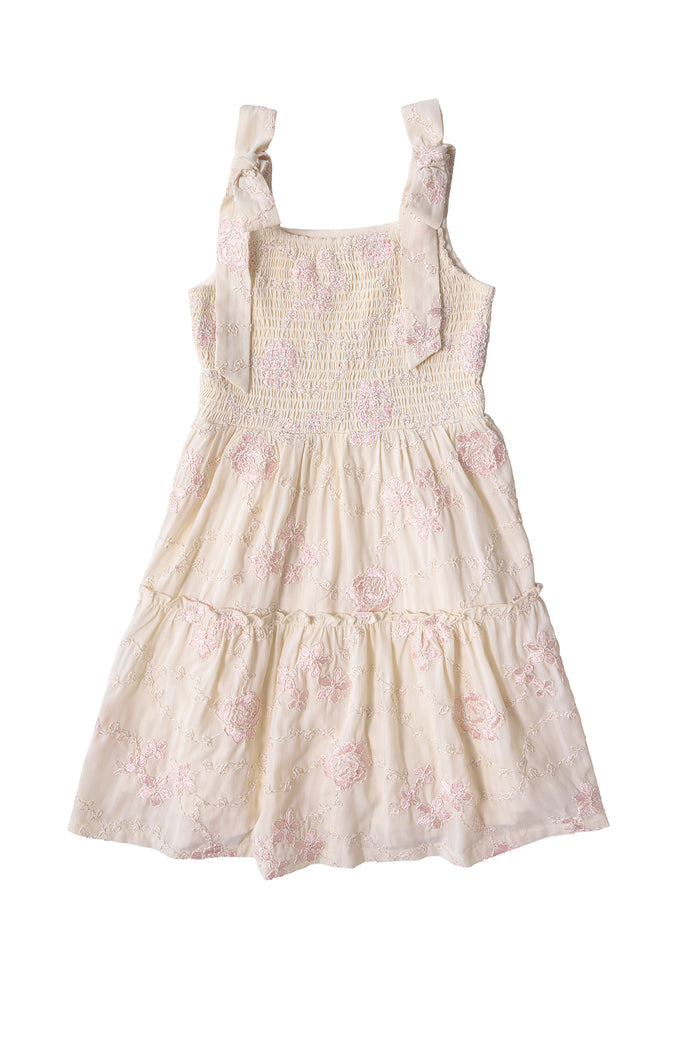 The Mini Tara Dress in Gilded Rose Stripe by Ivy City Co is a sleeveless girls’ dress featuring pink floral embroidery, a smocked bodice, tiered skirt, and bow-tied shoulder straps. Displayed on a white background.