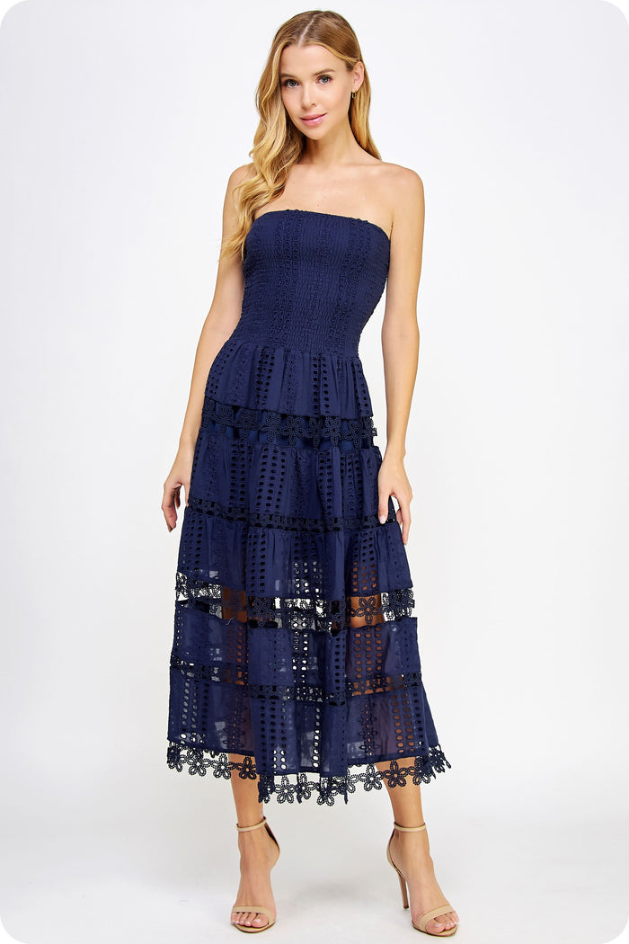 Woman wearing a navy strapless dress with lace details on a white background