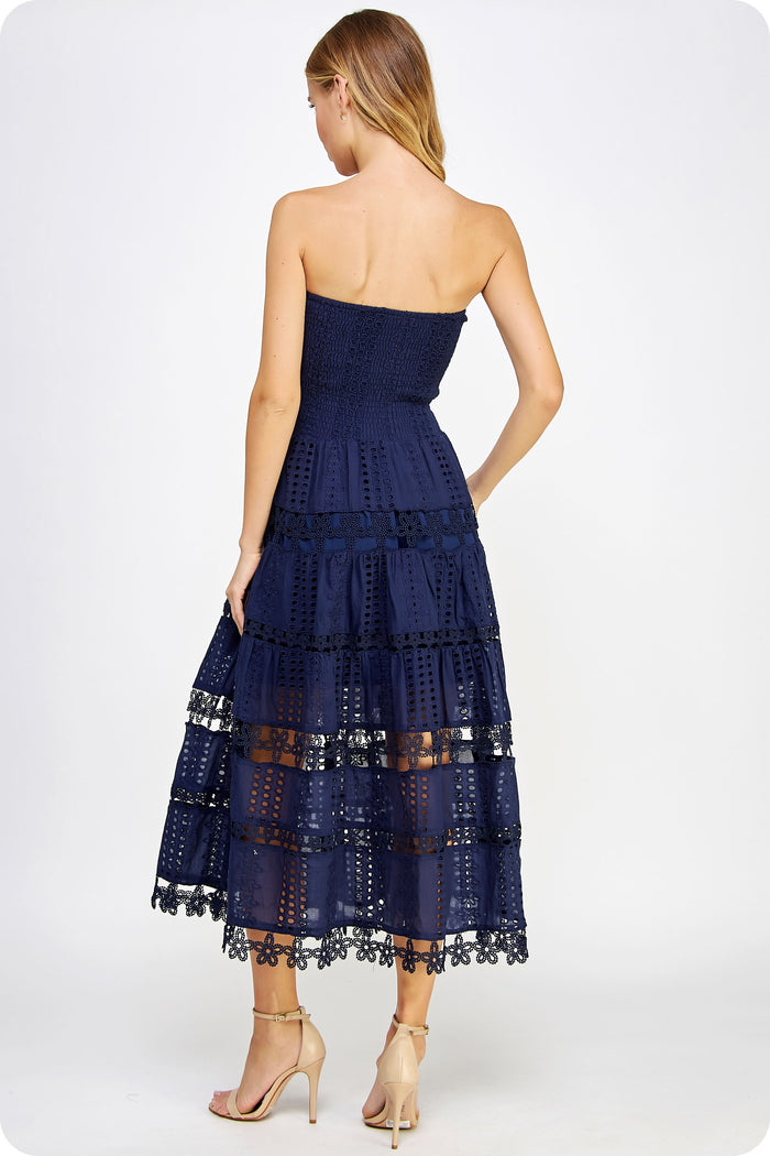Woman wearing a navy strapless dress with lace details on a white background