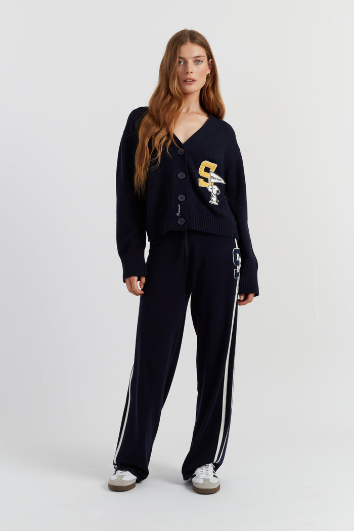 Woman wearing a navy cardigan and pants with a logo on a white background