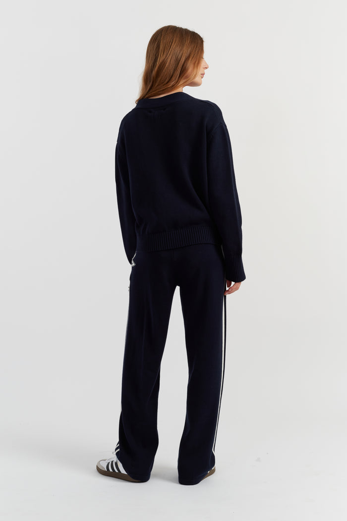 Person wearing a black tracksuit with white stripes on a light gray background
