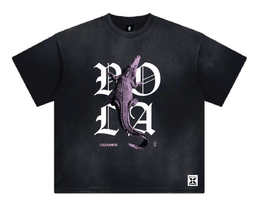 A black short-sleeve t-shirt with a graphic print featuring a crocodile over the letters 'NOLA' in white gothic font, with 'XGAMES '26' printed below.