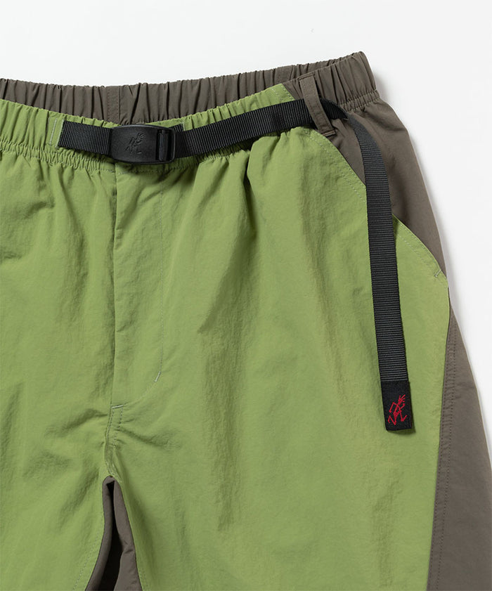 Close-up view of jade green Gramicci Nylon Block Shorts on a light-tone background.
