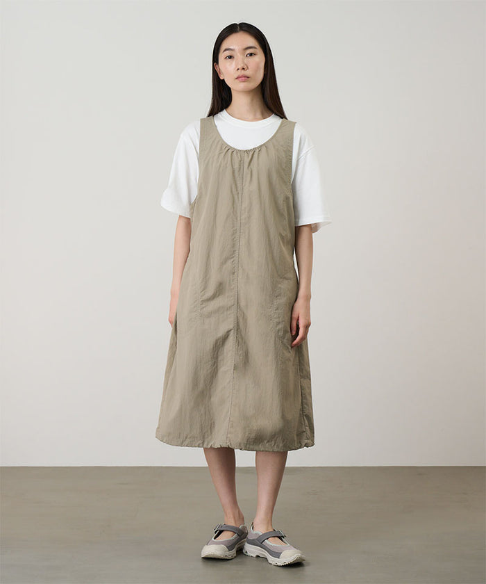 Model wearing a milk tea colored Gramicci Nylon Dress and a white shirt on a light-tone background.