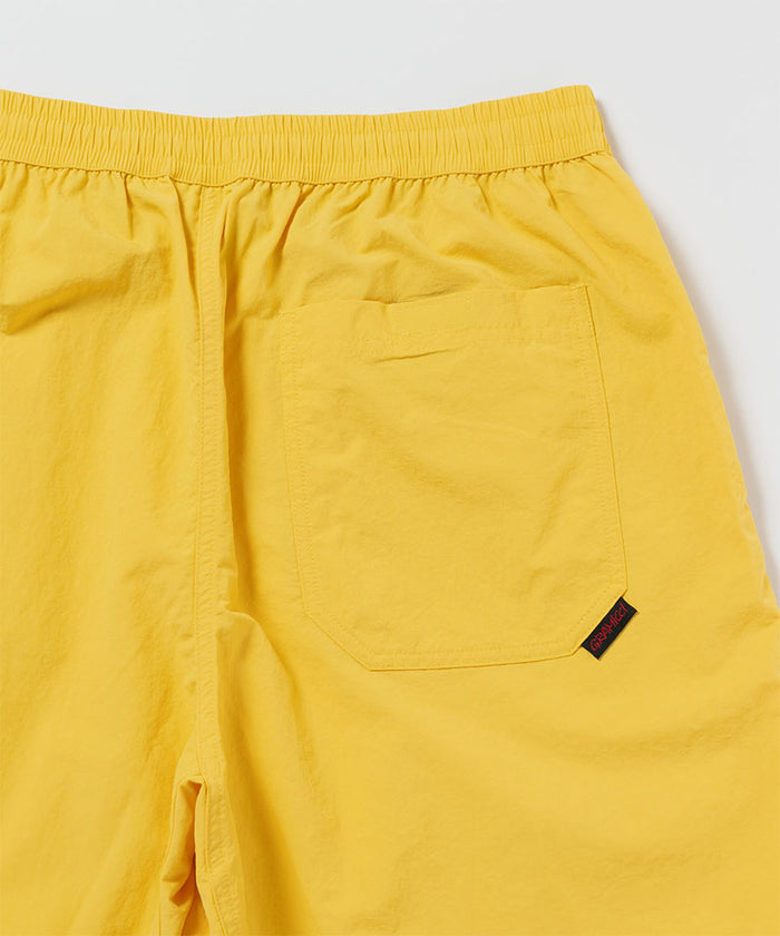 Close-up of banana colored Gramicci Nylon Reef Shorts on a light-tone background.