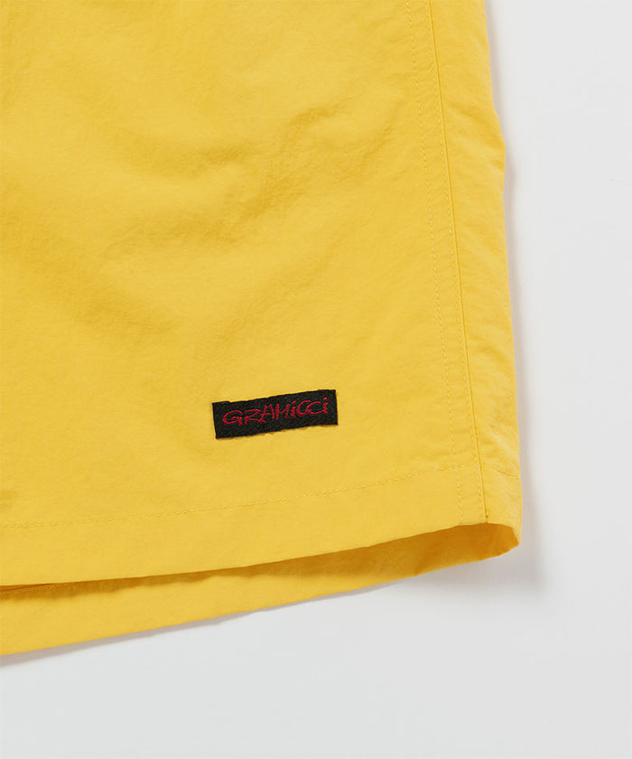 Close-up of banana colored Gramicci Nylon Reef Shorts on a light-tone background.