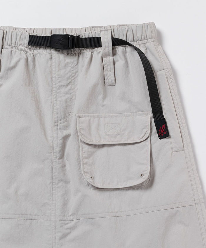 Close-up view of an ecru colored Gramicci Nylon Utility Skirt pocket and belt on a light-tone background.