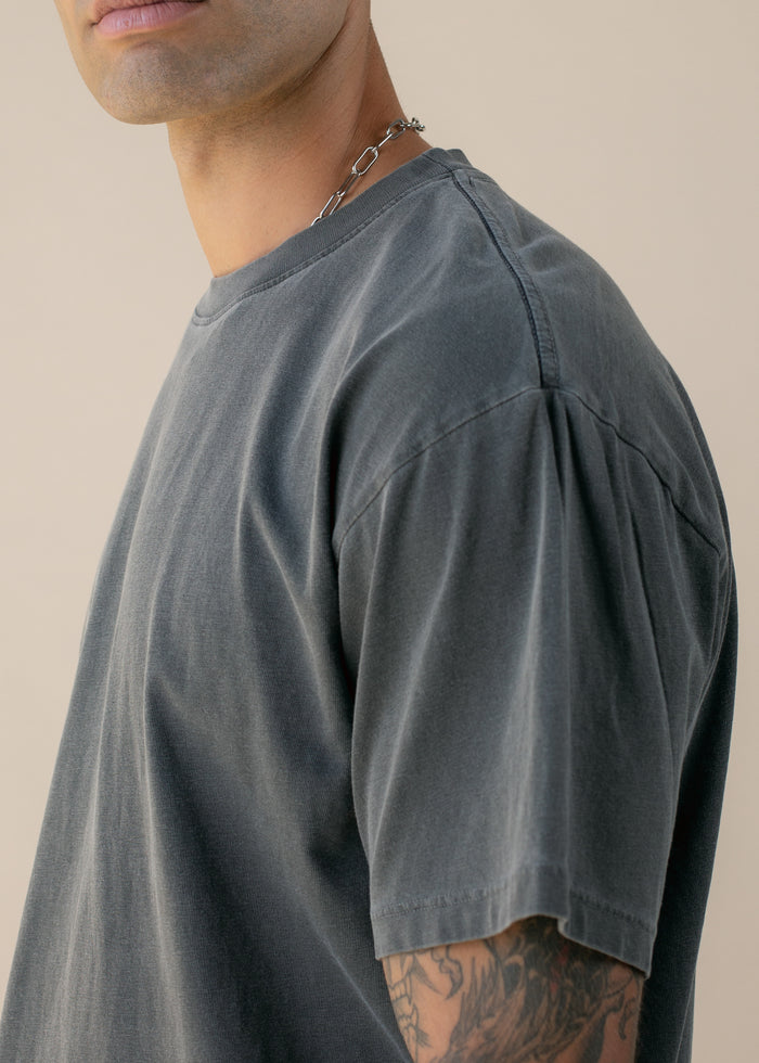 Closeup from side of person wearing a gray t-shirt with a neutral background