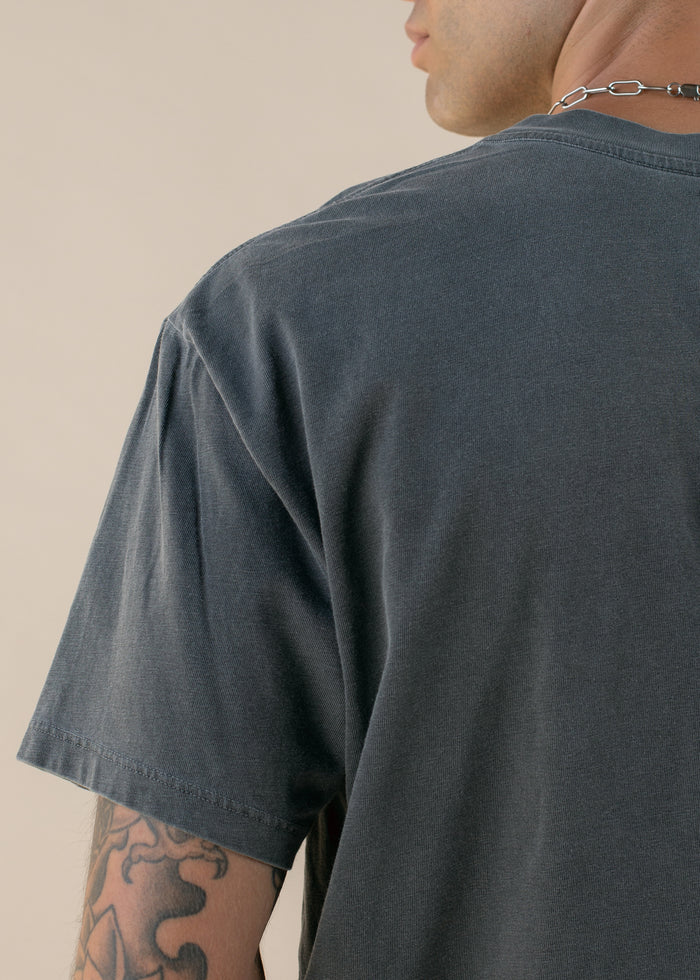Shot from behind of person wearing a dark gray t-shirt with a neutral background
