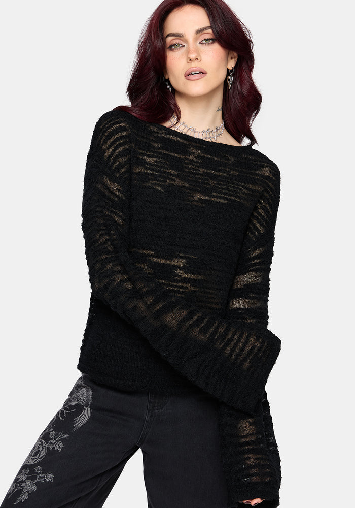 Woman wearing a black distressed jumper with long sleeves and back denim jeans on a white background