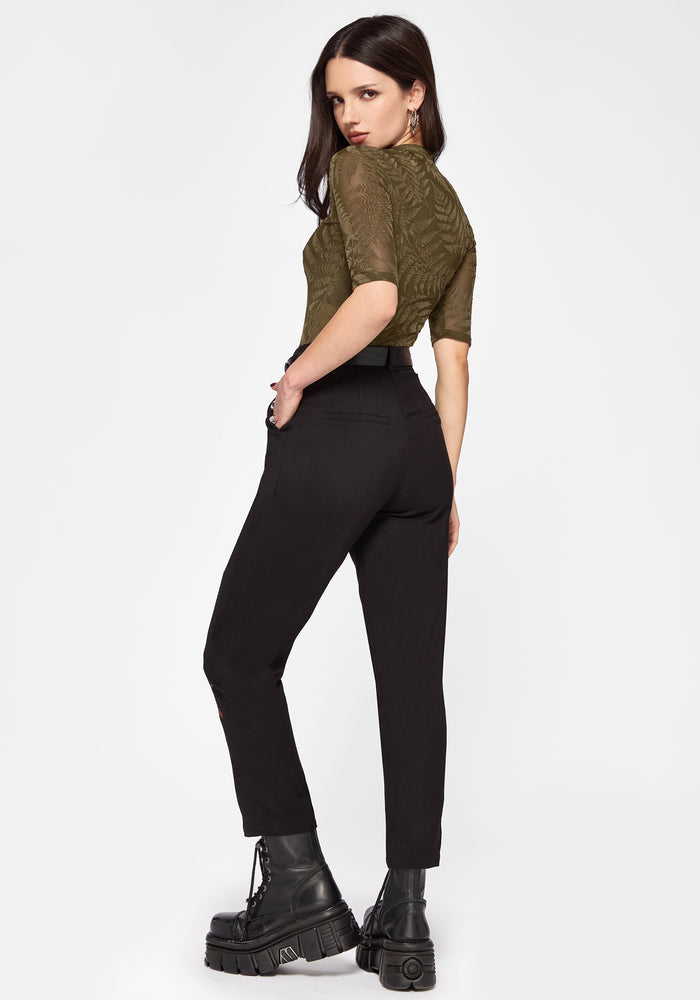 Woman wearing a green shirt and black pants on a white background