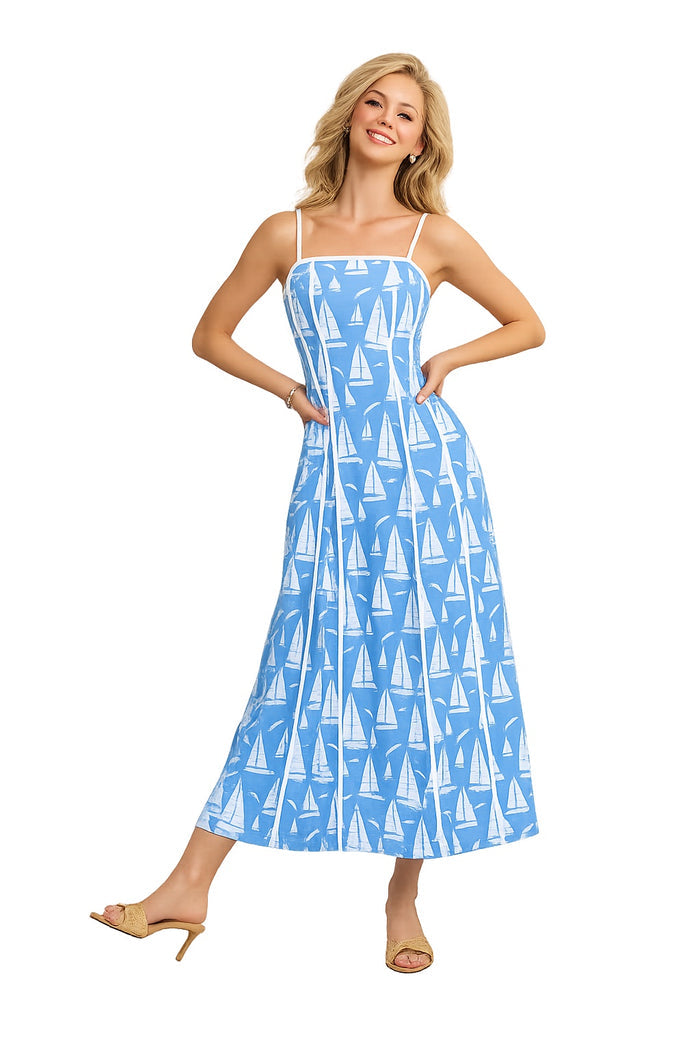 Woman wearing a blue dress with sailboat pattern on a white background with white trim and detailing