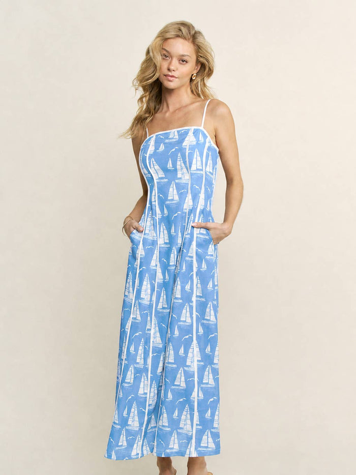 Woman wearing a blue dress with sailboat pattern on a white background with white trim and detailing