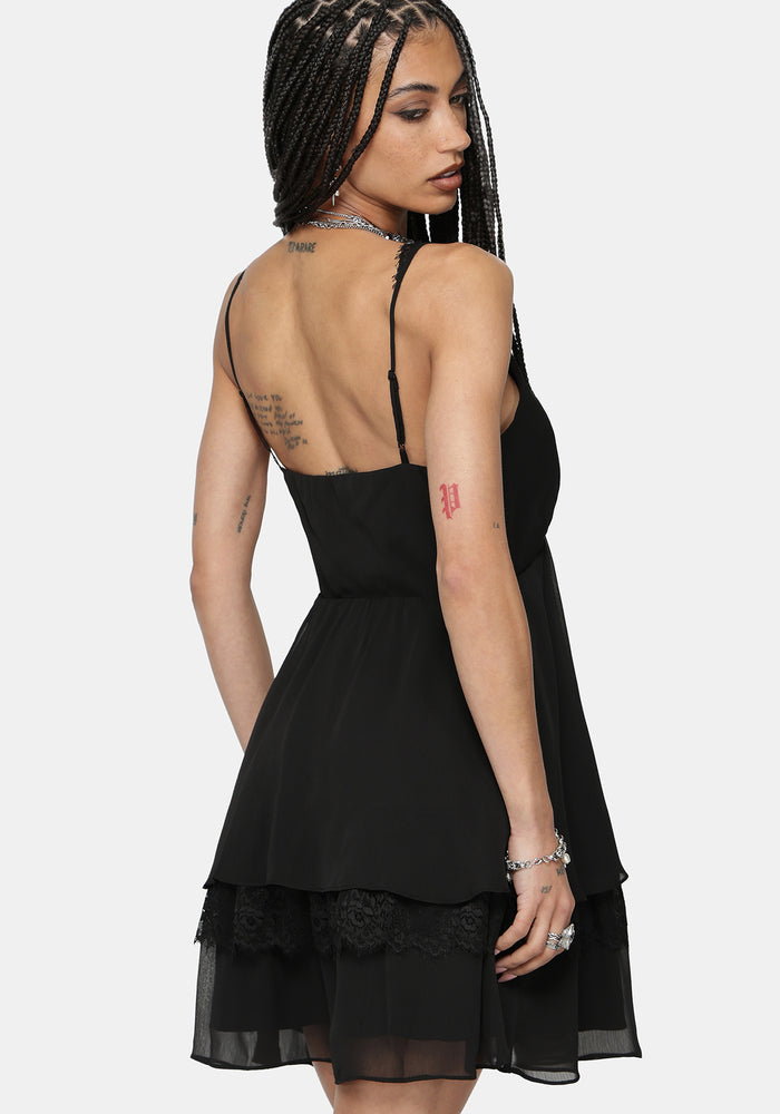 Woman wearing a black dress with sheer panels on a white background