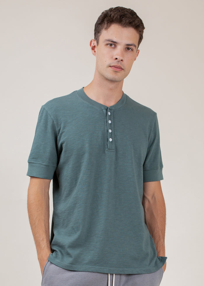 man wearing henley tee in pine green
