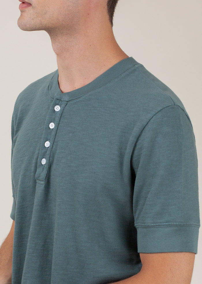 close up of man wearing henley tee in pine green