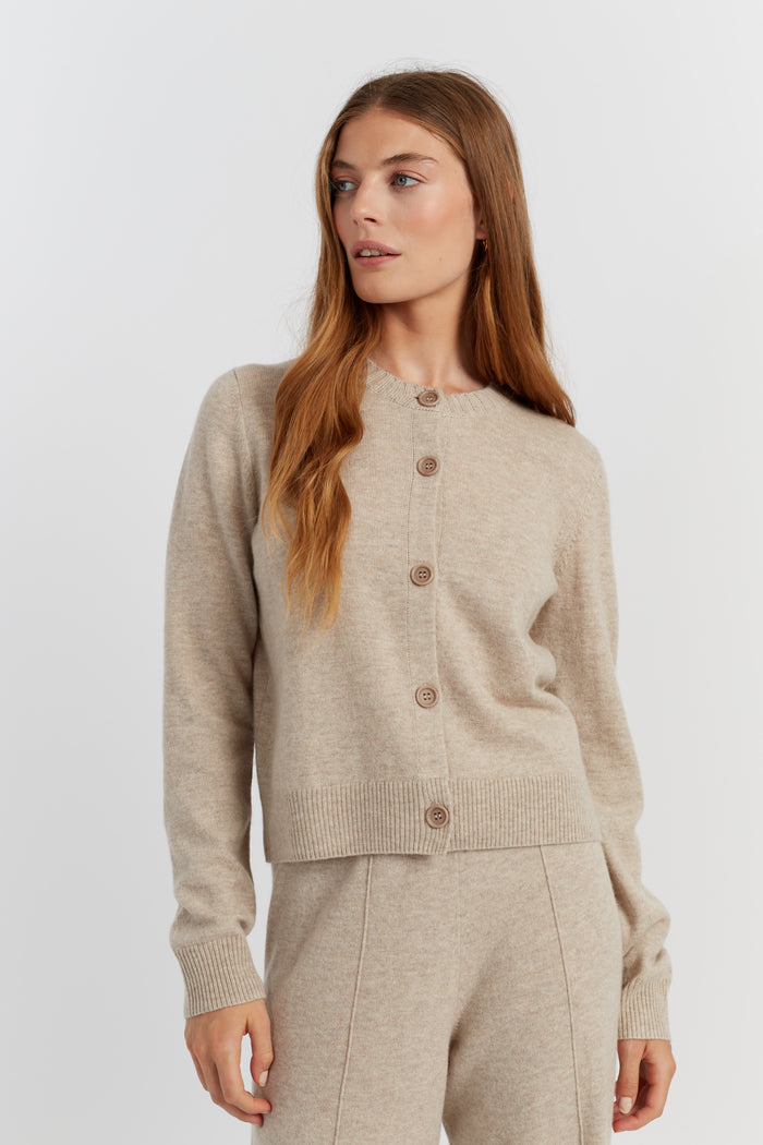 Woman wearing a beige cardigan and pants on a white background