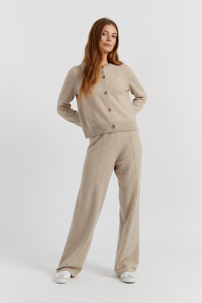 Woman wearing a beige cardigan and pants on a white background
