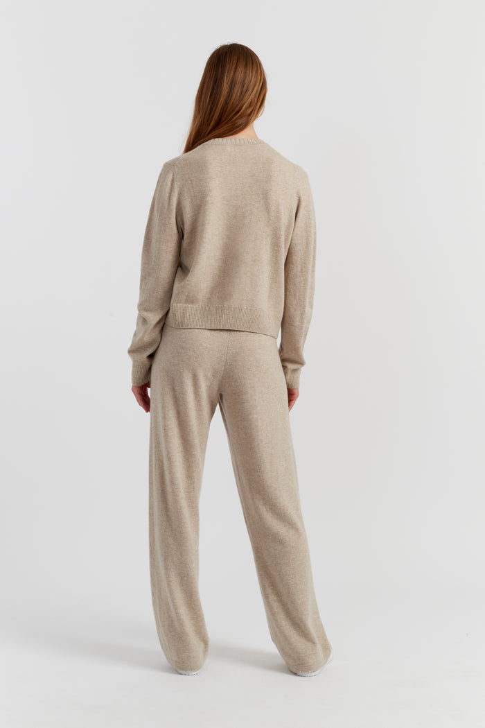 Person wearing a beige sweater and pants set on a white background