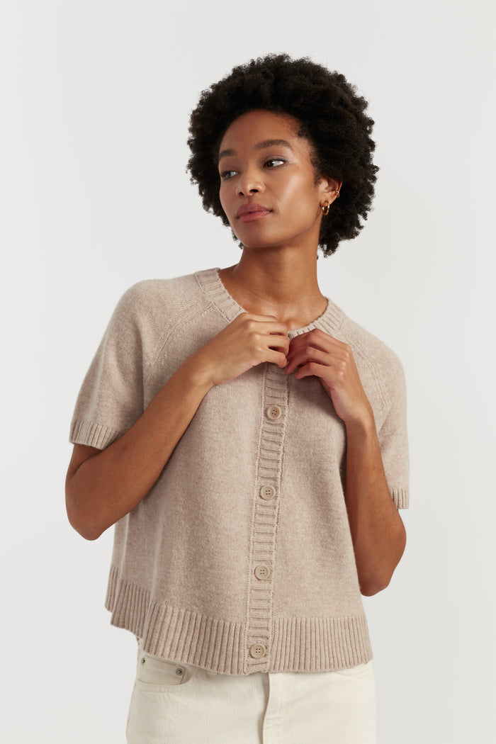Woman wearing a beige knit cardigan on a white background
