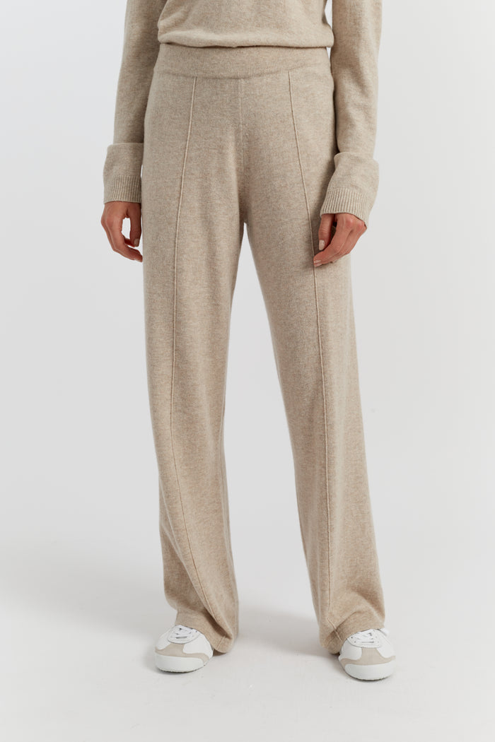 Person wearing beige pants and a sweater on a white background
