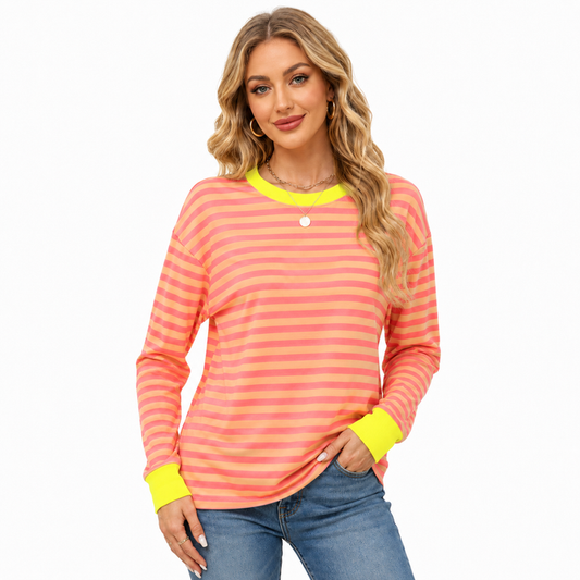 Women's coral and peach striped long sleeve top with neon yellow neckline and cuffs, modeled with blue jeans on white studio.