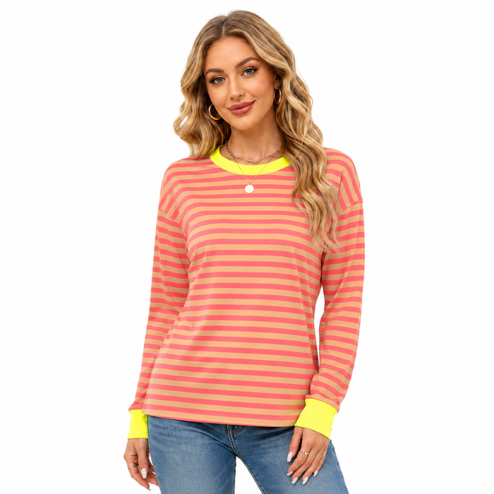 Women's coral and peach striped top with neon yellow trim, shown in a bright studio pose with blue jeans on a white backdrop.