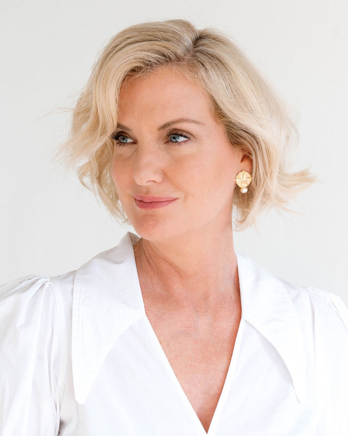 Woman with short blonde hair wearing a white shirt against a light background